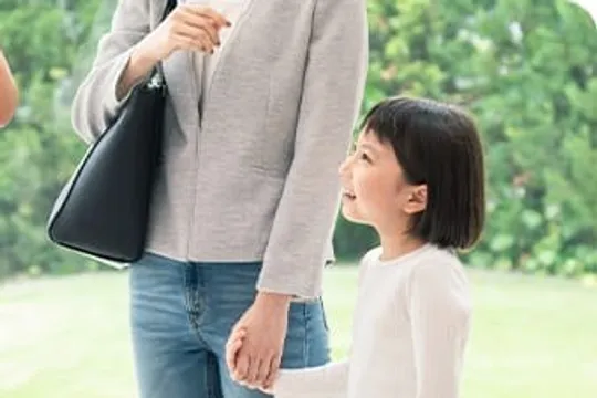 大人と手をつなぎ見上げて微笑む女の子