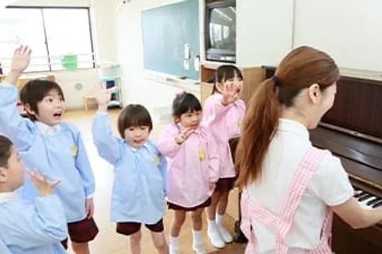 先生のピアノに合わせて園児が手を挙げる様子