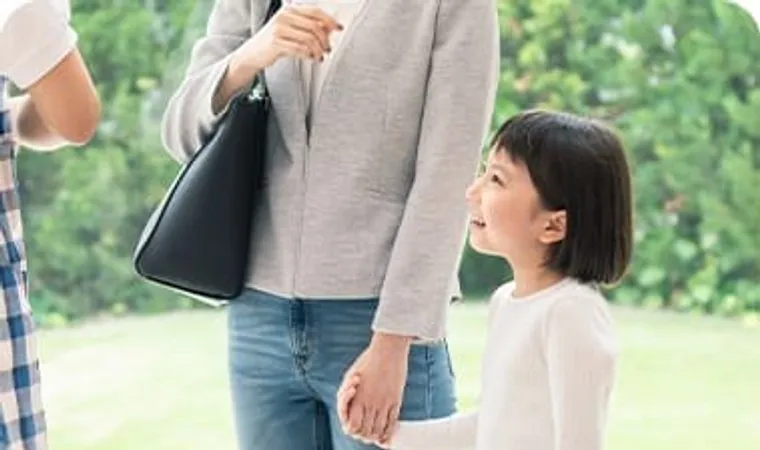 大人と手をつなぎ見上げて微笑む女の子