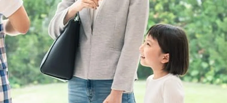 大人と手をつなぎ見上げて微笑む女の子